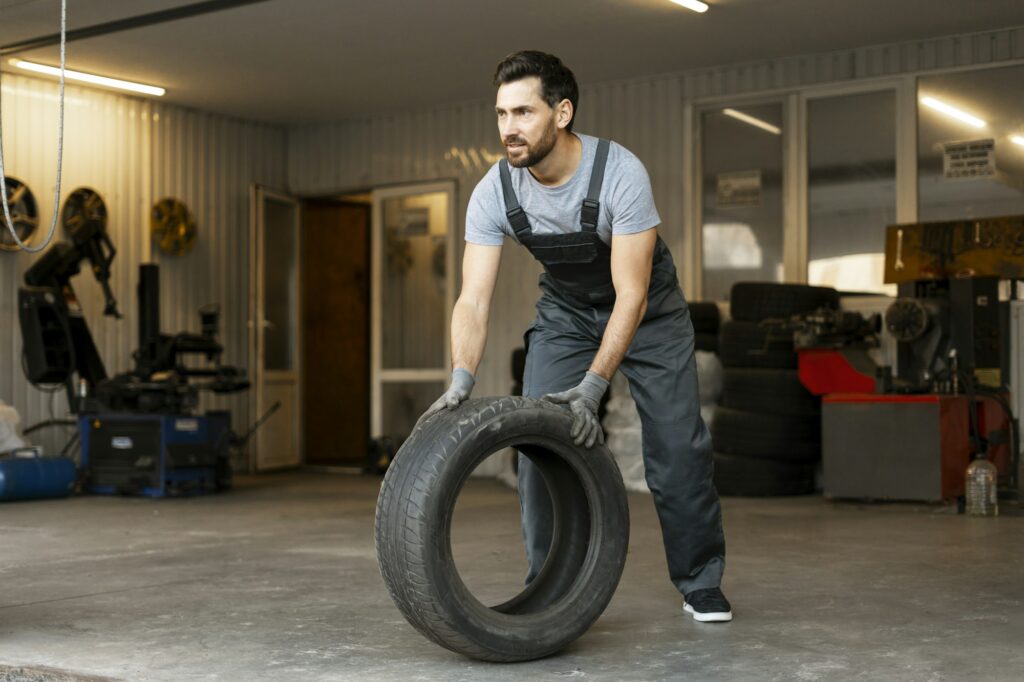 Mechanic lifting tire working in auto repair shop